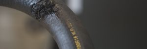 A burst rubber hydraulic hose that needs replaced