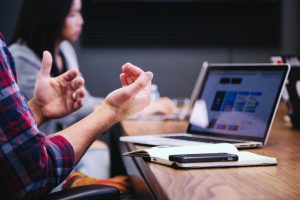 People at a table having a meeting with a laptop on the table