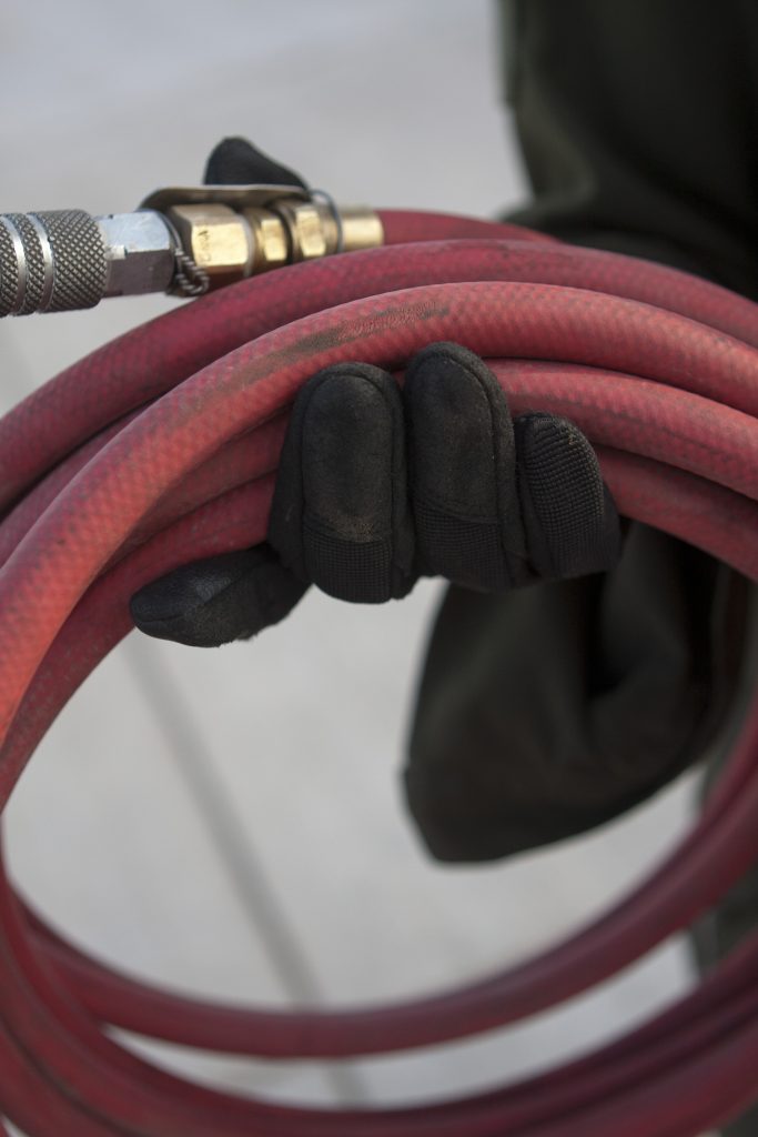 Person holding red air hose with brass fitting