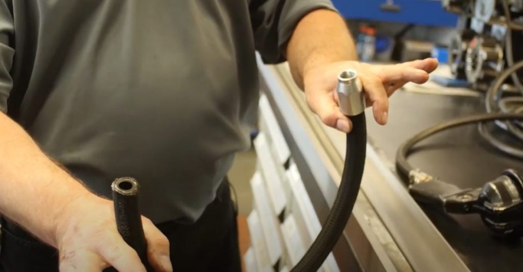 person holding hydraulic hose assembly