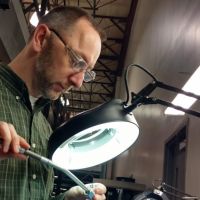 Quality engineer inspecting a tube fitting under a microscope